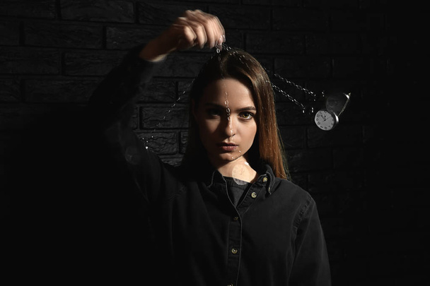 Hipnotizadora femenina con péndulo oscilante sobre fondo oscuro
 - Foto, imagen