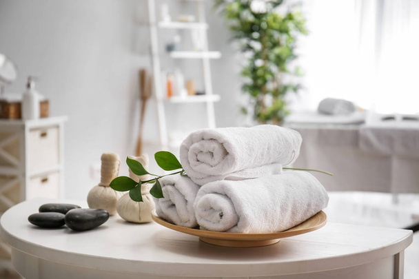 Towels, massage stones and herbal bags on table in spa salon - Photo, image