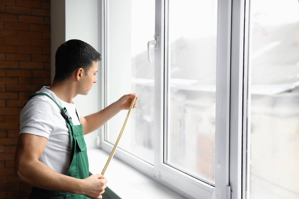 Чоловік працівник робить вимірювання вікна в квартирі
 - Фото, зображення