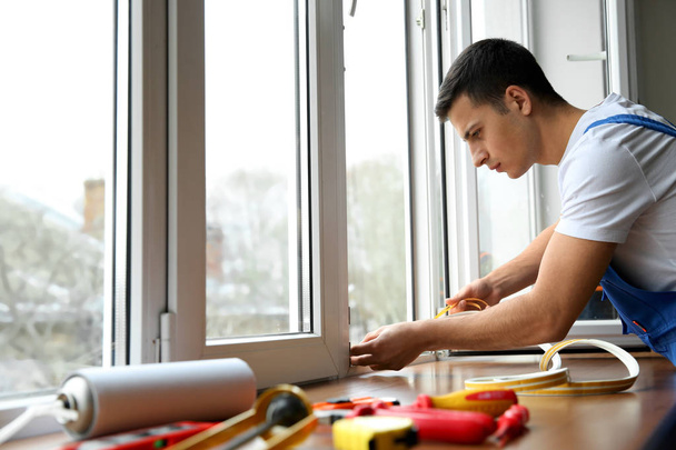Jeune travailleur installant une fenêtre dans un appartement
 - Photo, image