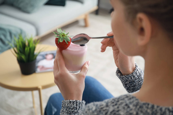 Young woman eating tasty yogurt at home - Photo, Image