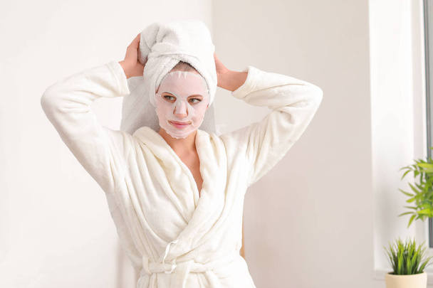 Beautiful young woman with sheet facial mask at home - Photo, Image