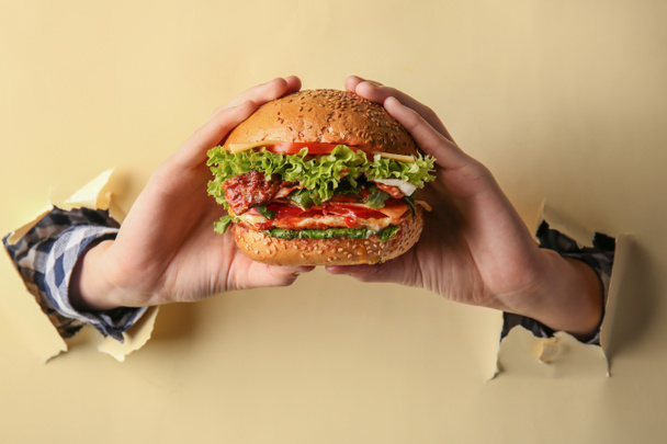 Female hands with tasty burger on color background - Foto, Imagen