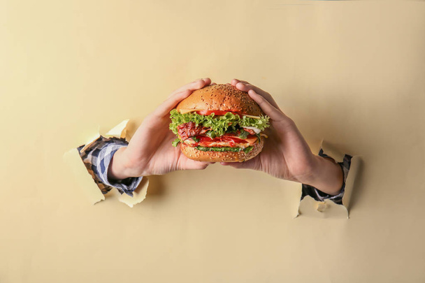 Female hands with tasty burger on color background - Zdjęcie, obraz