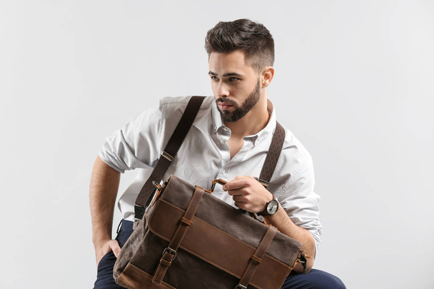 Fashionable young man with bag on light background - Valokuva, kuva