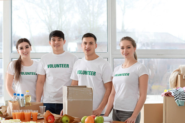 Νέοι εθελοντές με τα τρόφιμα για τους φτωχούς ανθρώπους σε εσωτερικούς χώρους - Φωτογραφία, εικόνα