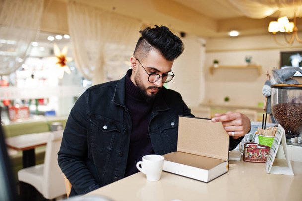 Uomo arabo indossare su giacca jeans neri e occhiali da vista in bevanda caffè
 - Foto, immagini