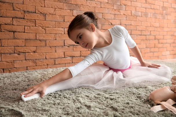 Schattige kleine ballerina uitrekken op zacht tapijt - Foto, afbeelding