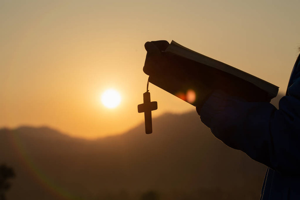 Frau hält eine heilige Bibel und ein Kreuz in ihren Händen und betet   - Foto, Bild