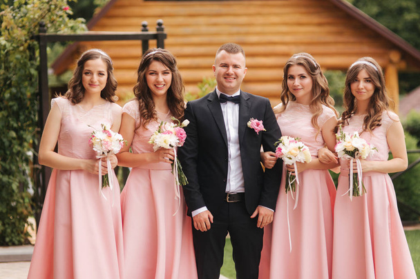 Handsome groom stand near beautiful bridesmaid with bouquets - Photo, Image