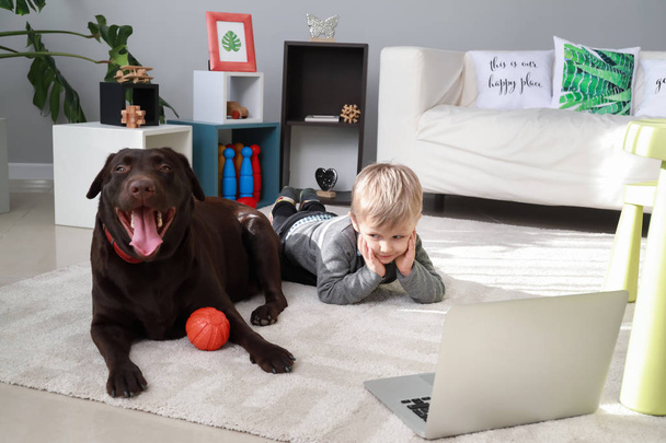 Netter kleiner Junge mit lustigem Hund, der zu Hause Cartoons guckt - Foto, Bild