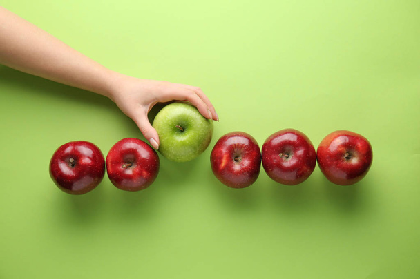 Naiskäsi maukkaita omenoita värillinen tausta. Ainutlaatuisuuden käsite
 - Valokuva, kuva