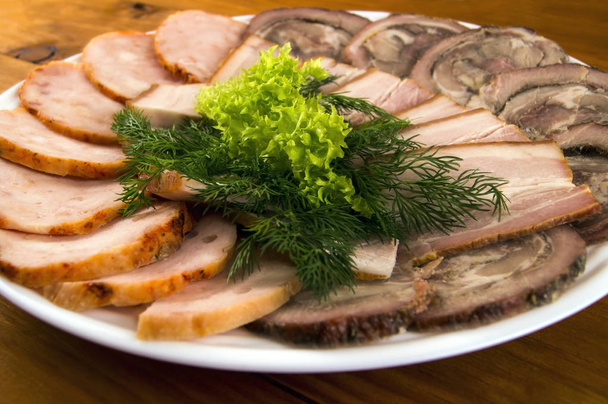 Sekaná, slaninou a klobásu, zdobené salátem a koprem na dřevěné pozadí - Fotografie, Obrázek