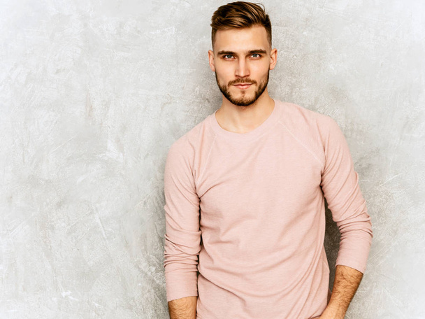 Portrait of handsome confident hipster lumbersexual businessman model wearing casual summer pink clothes. Fashion stylish man posing against gray wall. Daylight - 写真・画像
