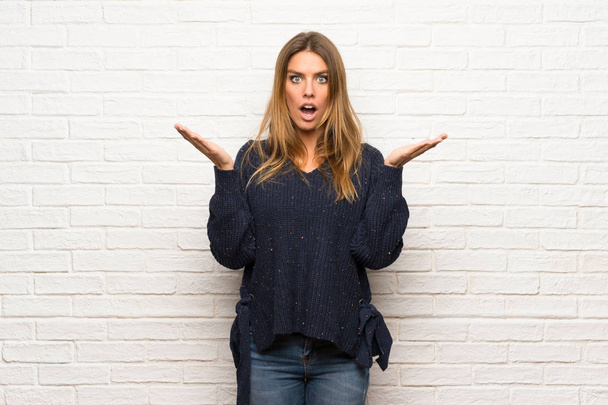 Blonde woman over brick wall with surprise facial expression - Photo, Image