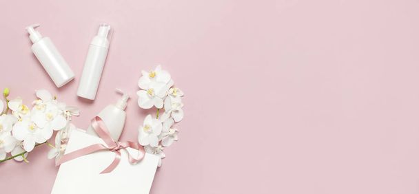 Tasainen lay top näkymä Valkoinen kosmeettinen pullo säiliöt lahjapussi Valkoinen Phalaenopsis orkidea kukkia vaaleanpunainen tausta. Kosmetiikka SPA brändäys mallinnus Natural orgaaninen kauneus tuotteen käsite Minimalismi tyyli
 - Valokuva, kuva