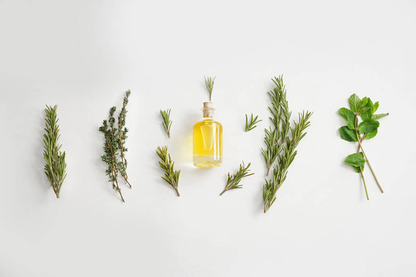 Bottle of oil with different herbs on white background - Фото, зображення