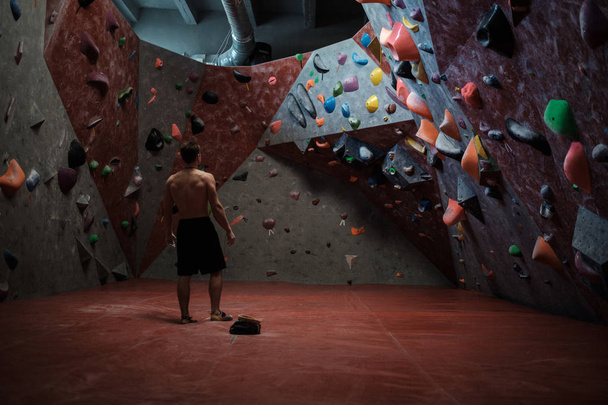Athletic man practicing in a bouldering gym - Фото, изображение