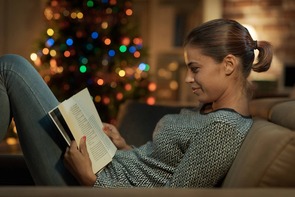 Smiling woman reading a book on Christmas Eve - Valokuva, kuva