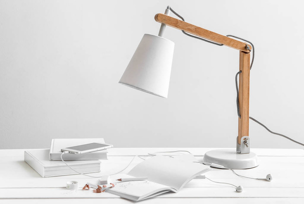 Quaderni, lampada e cellulare su tavolo bianco
 - Foto, immagini