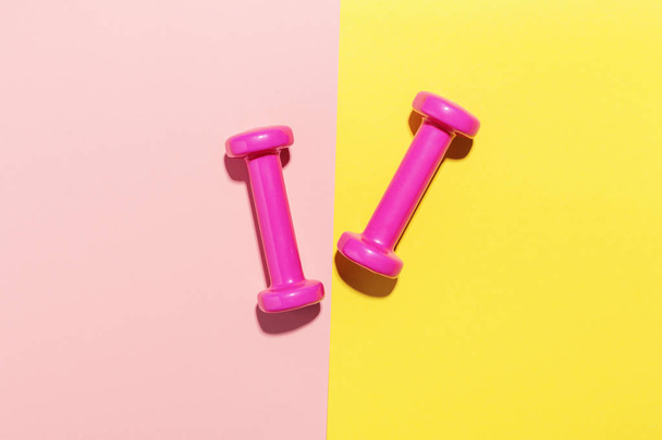 Dumbbells flat lay on pink and yellow - 写真・画像
