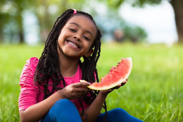 Outdoor portrait of a cute young black little girl eating waterm - Zdjęcie, obraz