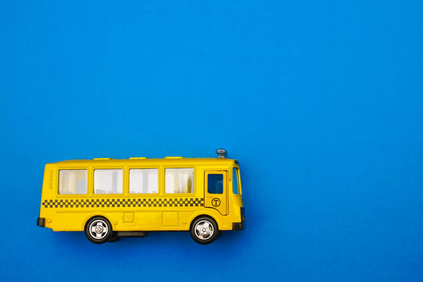 yellow school bus plastic and metal toy model isolated on blue paper background. empty copy space for inscription.  - Photo, Image