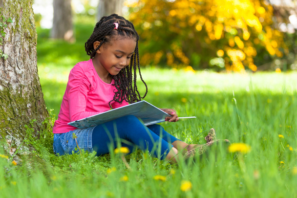 Außenporträt eines netten jungen schwarzen Mädchens beim Lesen eines Buhs - Foto, Bild