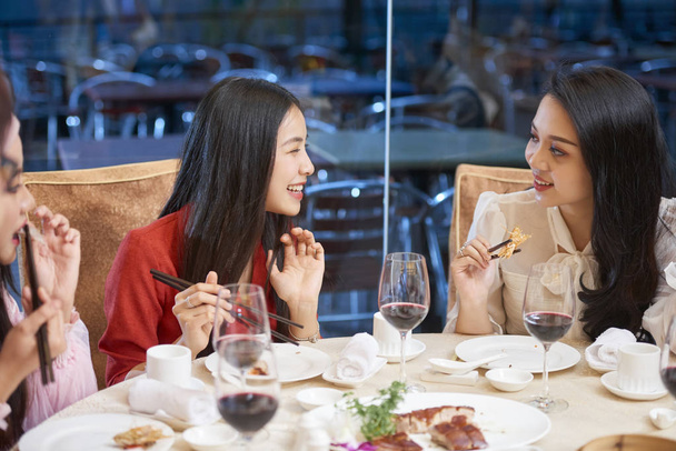 Les jeunes jolies femmes asiatiques parlent et bavardent lors du dîner
 - Photo, image