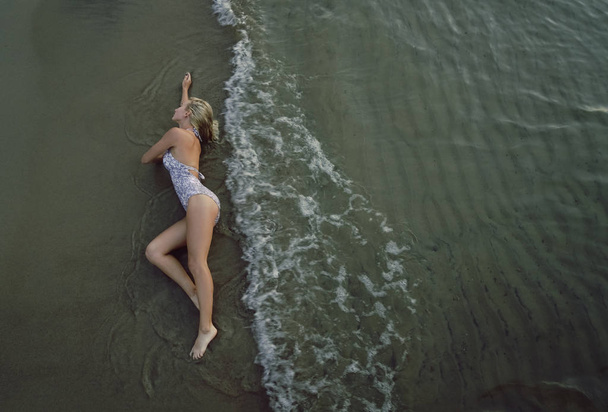 top view. Beautiful young woman on wet sand - Fotó, kép