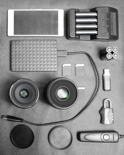 Workspace of photographer. Top view with black table, photo flas, lens, smartphone, remote control, compact disk and battery charger.  - Фото, изображение