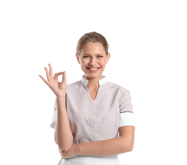 Portret van mooie vrouwelijke huishoudster weergegeven: Ok gebaar op witte achtergrond - Foto, afbeelding