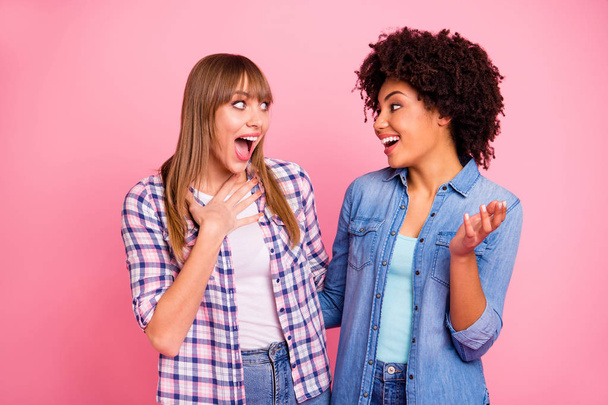Close up photo two diversity she her ladies different race chatterbox good mood speak tell over news spread share news wear casual jeans denim checkered shirt cloth outfit isolated pink background - Foto, afbeelding