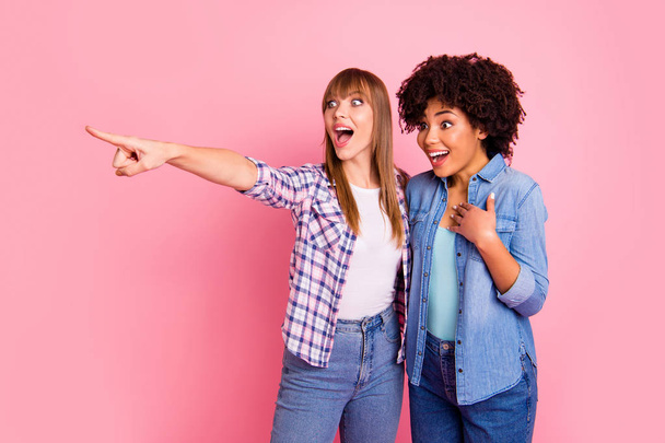 Close up photo two diversity she her ladies different race wondered speak tell over news share rumours show finger empty space wear casual jeans denim checkered shirt outfit isolated pink background - Zdjęcie, obraz
