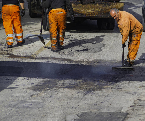 Pracovník regulovat pokládání nový asfalt opravit hrbol na silnici. - Fotografie, Obrázek