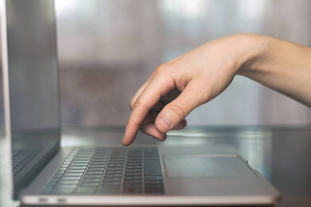 Um único dedo pressionando o botão do teclado no laptop com borrão
 - Foto, Imagem