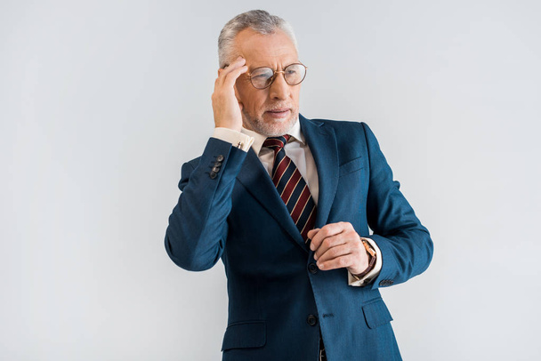 mature businessman in suit having headache while standing isolated on grey - Photo, Image