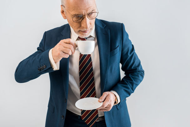vista aerea di maturo uomo d'affari che tiene piattino e tazza isolati su grigio
 - Foto, immagini