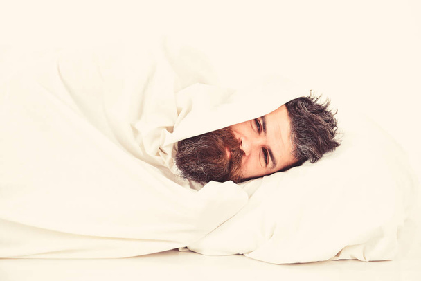 Guy with beard hides under blanket. Weekend leisure concept. - Fotó, kép