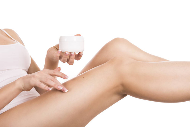 Attrayant jeune femme appliquant la crème à ses jambes isolées sur blanc
 - Photo, image