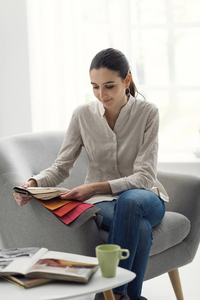 Young woman choosing the best upholstery for the armchair - Foto, imagen