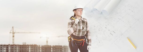 A female construction worker in safety helmet holds a hammer - Photo, image
