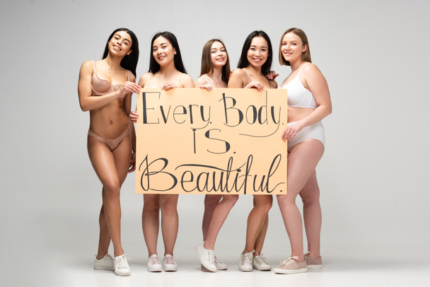 fünf hübsche multikulturelle Mädchen mit einem Plakat mit der Aufschrift "Jeder Körper ist schön" - Foto, Bild