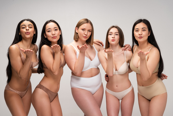 fünf hübsche multikulturelle Mädchen in Dessous senden Luftküsse isoliert auf grau, Body-Positivity-Konzept - Foto, Bild