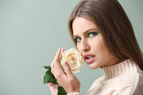 Beautiful young woman with bright makeup and flower on color background - Foto, immagini
