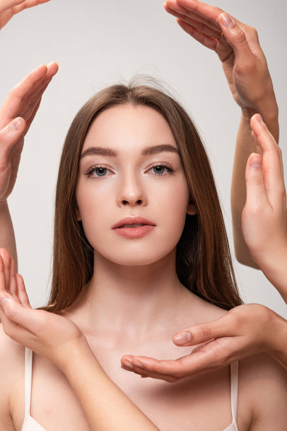 portrait of beautiful young woman surrounded by female hands isolated on grey - Fotoğraf, Görsel