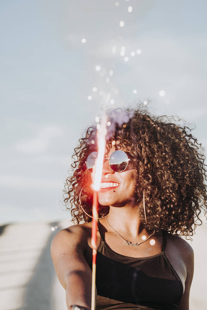 Young afro woman with sparklers and sunglasses - Fotografie, Obrázek