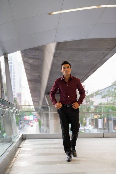 Joven guapo empresario hispano caminando y pensando en la pasarela
 - Foto, imagen