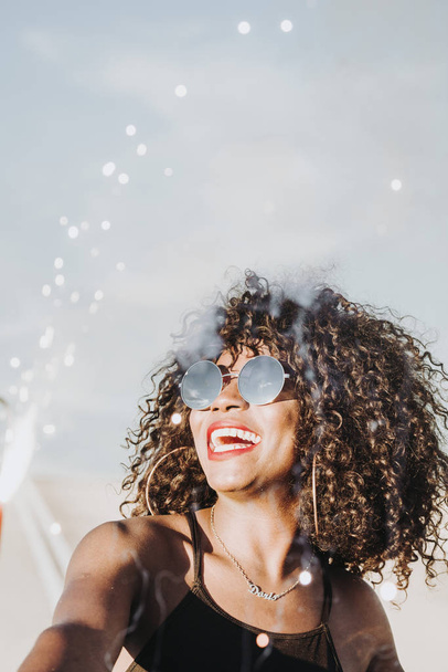Young afro woman with sparklers and sunglasses - Фото, изображение