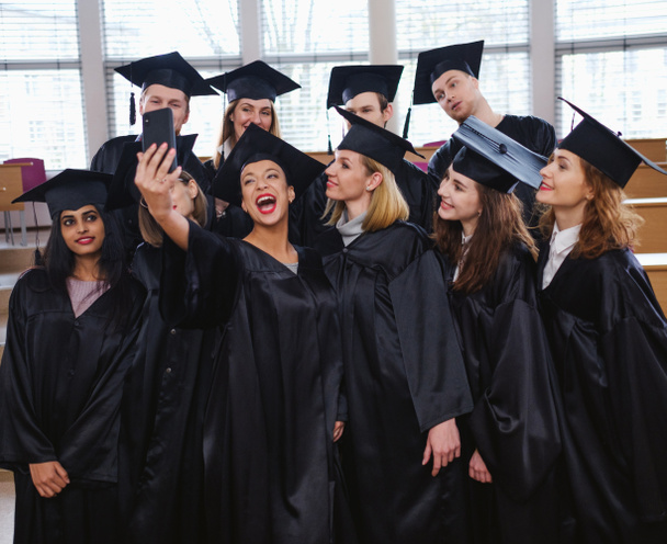 Grupo étnico multi de estudantes graduados que tomam selfie
 - Foto, Imagem